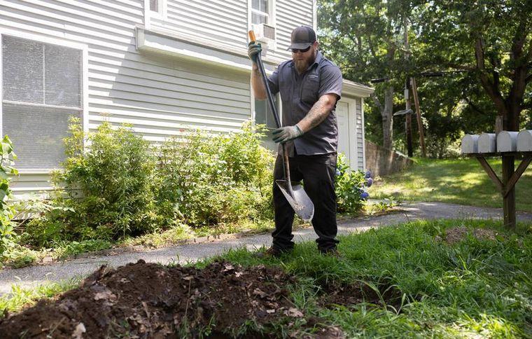 A crew member working on a septic repair in a dug yard.