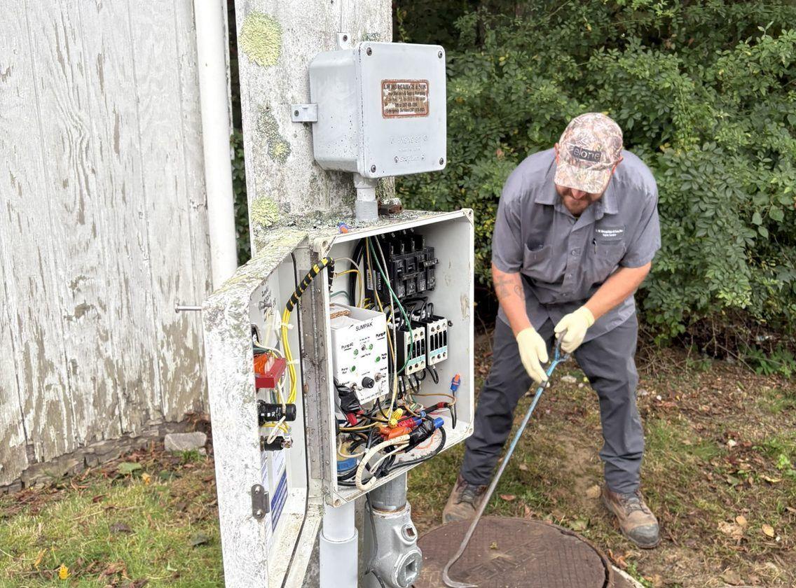 A lift station control panel mounted beside a pump chamber, with the alarm light on top of the enclosure.
