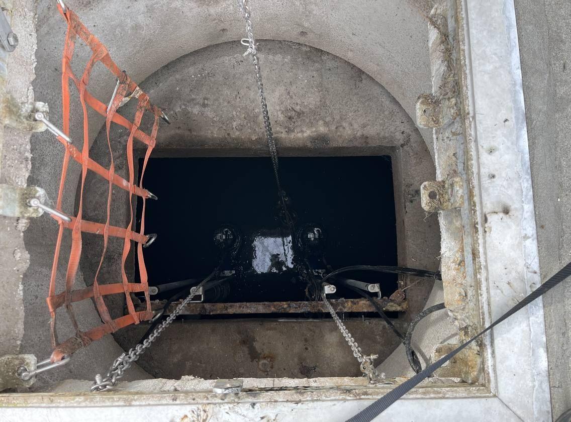 An open lift station vault with the pump and float assembly visible during a service call.