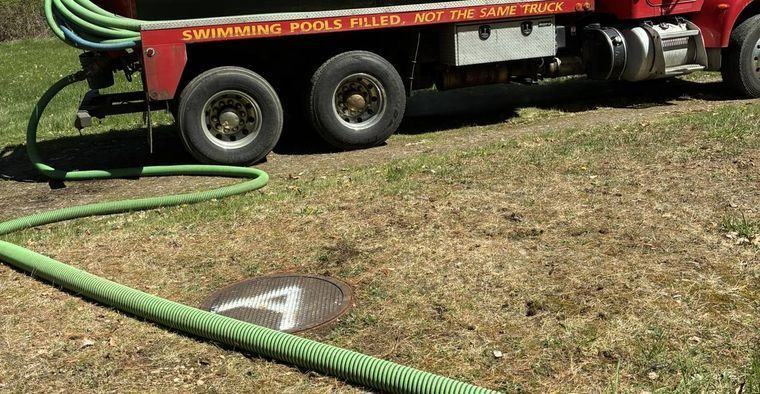 A crew member opening a septic tank lid in a yard.