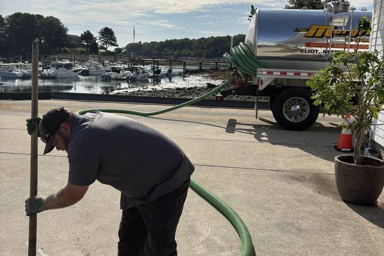 A Morgridge technician running a suction hose from the tanker at a waterfront property in Eliot.