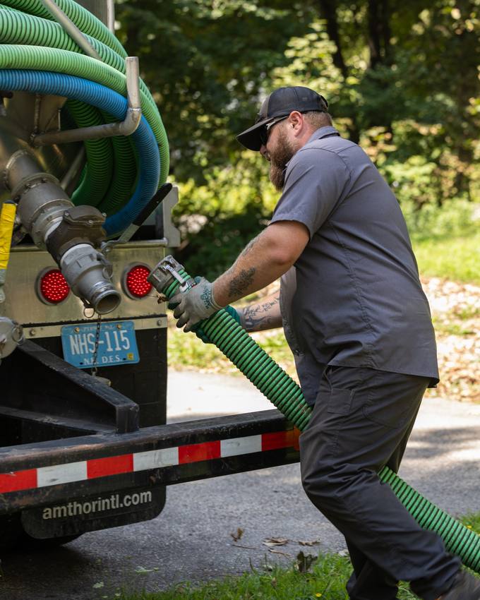 A technician pulling the suction hose off the truck on a job.